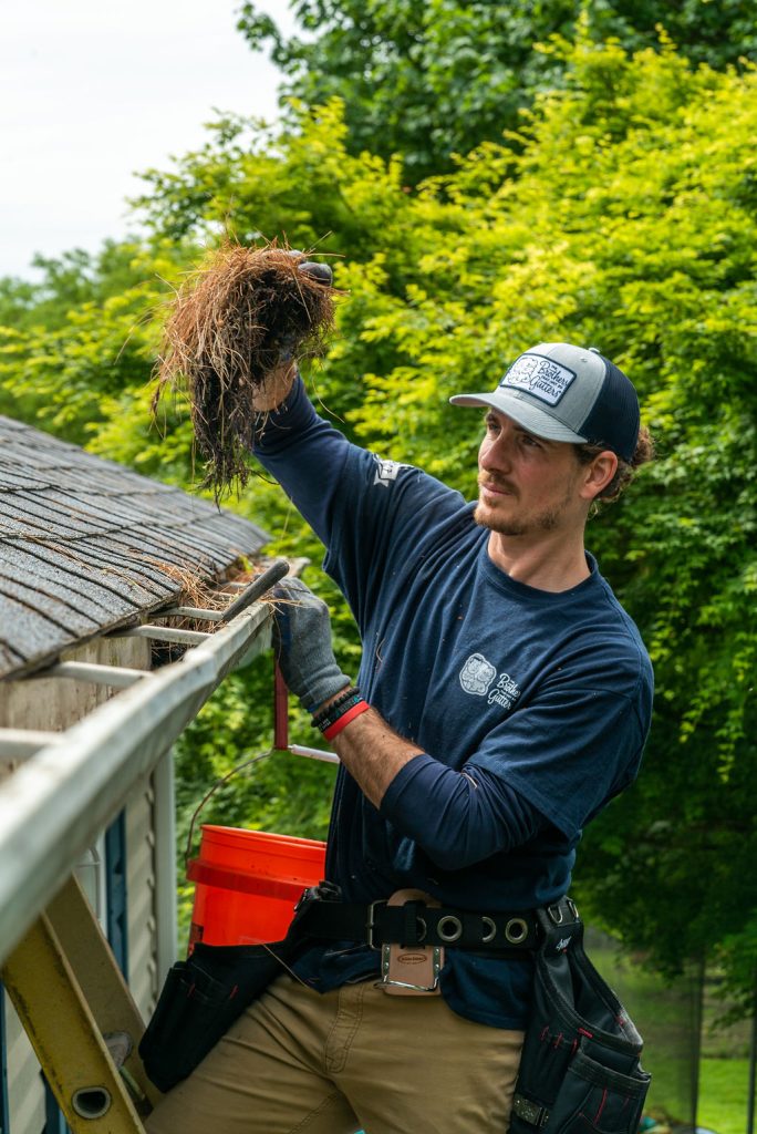 gutter cleaning services - tech holding a wad of debris from gutter