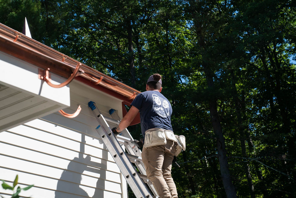 copper gutters being installed by a tech on a ladder